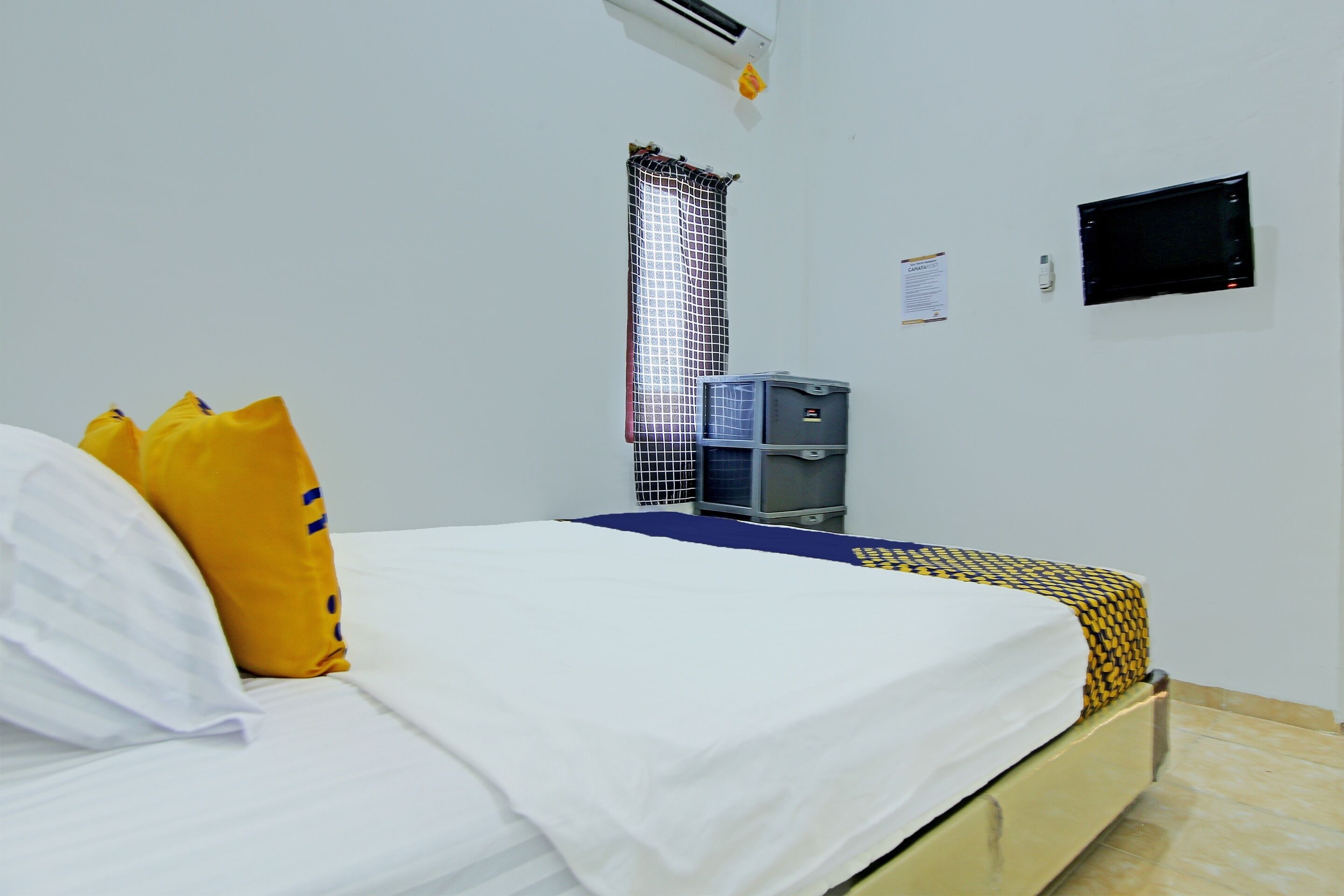 A hotel room with a bed, a water dispenser, a television, and a curtain.