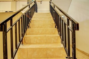 A staircase with beige tiles and black metal railings.