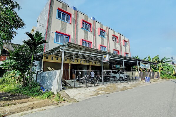 A multi-story building with a covered entrance area, a metal fence, and parked motorcycles.