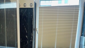 A bathroom with a bathtub, toilet, and a window with blinds. - Apartment MARINA (Bremerhaven)