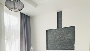 A modern hotel room with a bed, a sofa, a TV, and a large abstract painting on the wall. - Apartment MARINA (Bremerhaven)