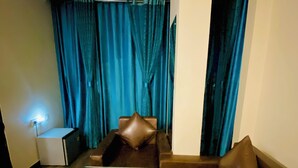 A modern living room with a sectional sofa, a coffee table, and a small side table. - Hotel Mock Orange (Jaipur)