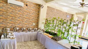 A buffet setup with multiple serving stations, a stone wall, and bamboo plants. - Hotel Mock Orange (Jaipur)