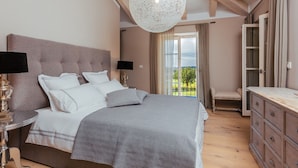 A bedroom with a bed, bedside tables, a dresser, a chandelier, and a view of the outdoors. - Arabela in Baderna With 4 Bedrooms and 3 Bathrooms (Porec)