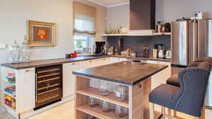 A modern kitchen with a central island, built-in wine rack, and a seating area with a cushioned chair. - Arabela in Baderna With 4 Bedrooms and 3 Bathrooms (Porec)