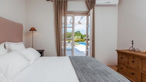 A bedroom with a bed, a nightstand, a dresser, and a view of a swimming pool. - Arabela in Baderna With 4 Bedrooms and 3 Bathrooms (Porec)