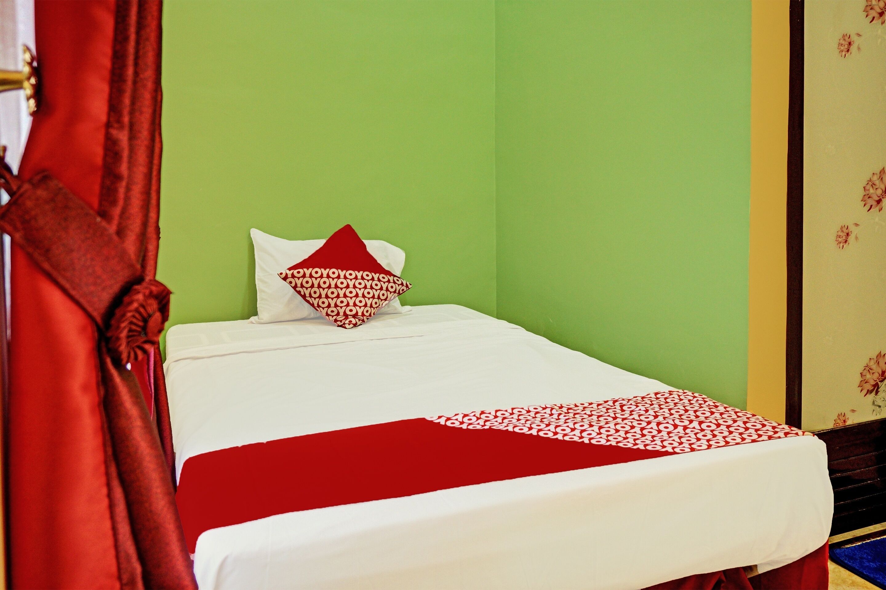 Un lit avec une couvre-lit blanche et rouge, un oreiller rouge et un rideau rouge.