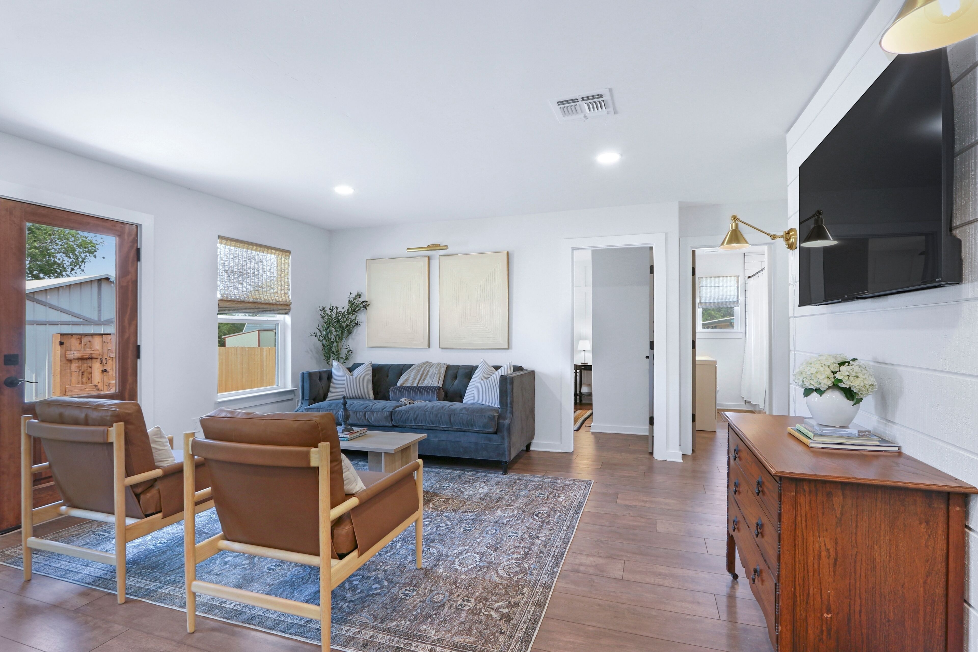 A modern living room with a sofa, chairs, a coffee table, and a TV.