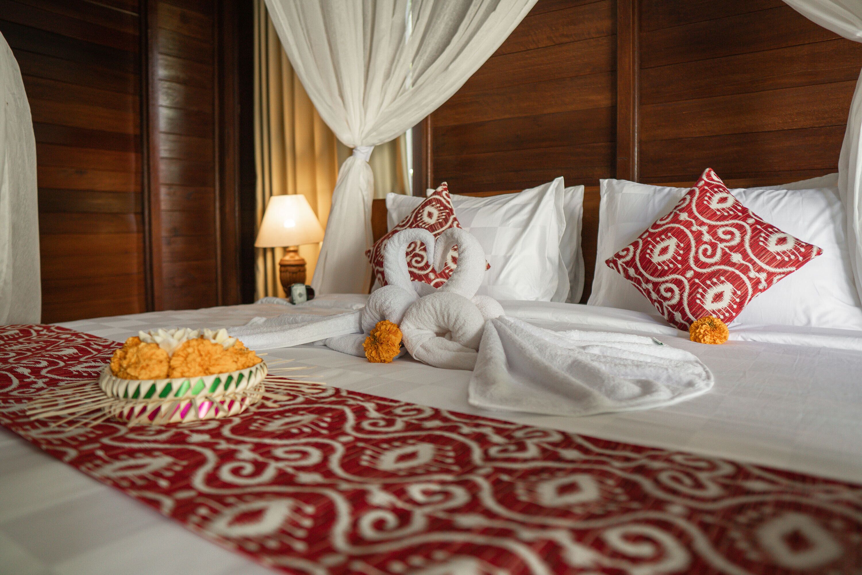 Ein Hotelzimmer mit Bett, weißen Leinen, einer roten und weißen Bettdecke und einer Obstschale auf dem Bett.