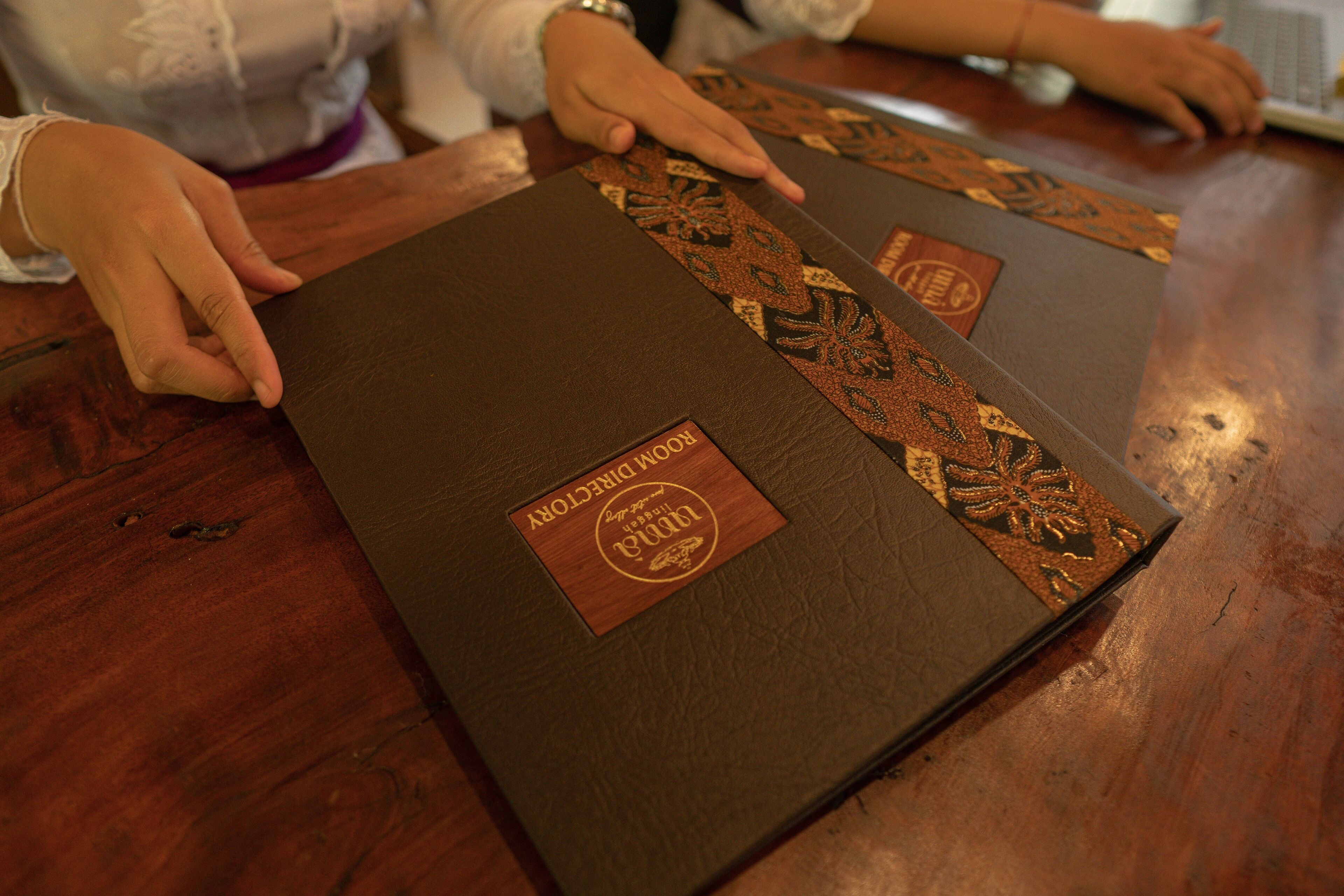 A wooden table with two brown book-like objects with embossed designs and a label that reads "ROMAN D'ARCY".