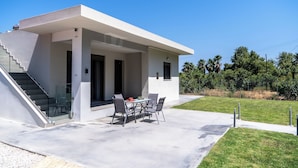 A modern house with a covered patio, a staircase, and a glass door leading to the interior. - Villa Emily (Voukolies, Chania)