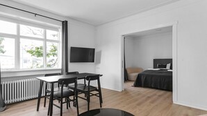 A modern room with a dining table, chairs, a TV mounted on the wall, a bed, and a radiator.