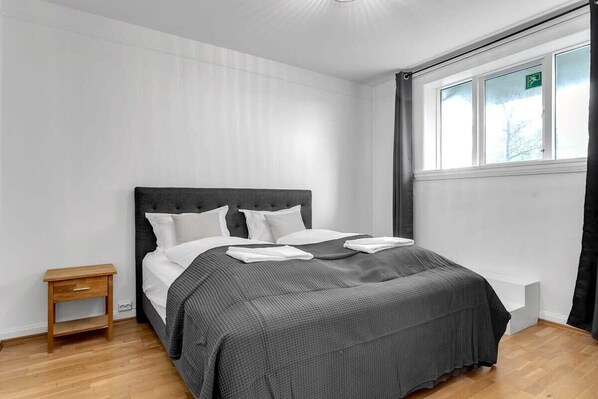 A neatly arranged bedroom with a bed, bedside table, and a window with curtains.