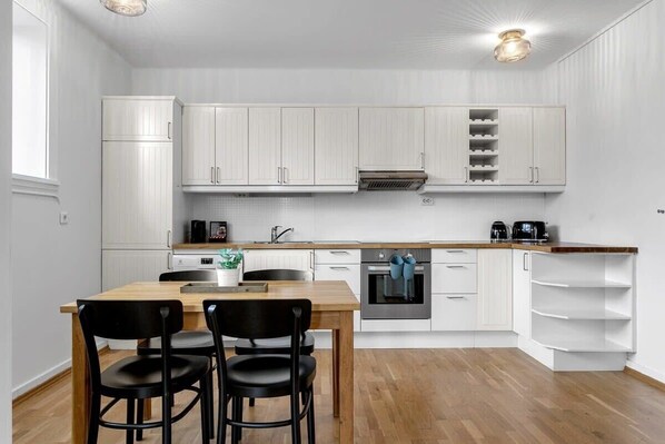 A modern kitchen with white cabinetry, a wooden dining table, and black chairs.
