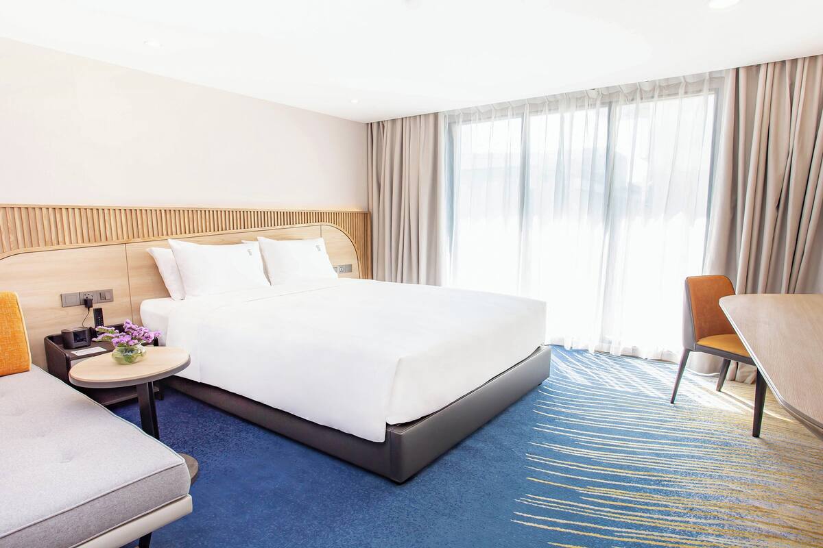 Een hotelkamer met een groot bed, een bureau, een stoel en een televisie.