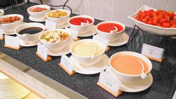 A buffet with various dishes including soup, salad, and a bowl of tomatoes.