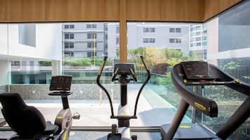 A home gym with two elliptical machines and a treadmill, large windows offering a view of the cityscape.