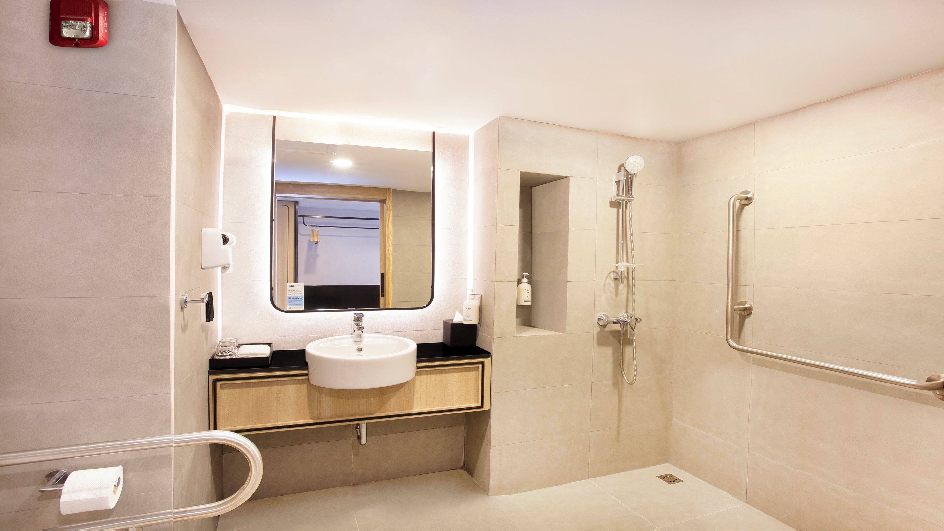 Un baño moderno con lavamanos, espejo y ducha.