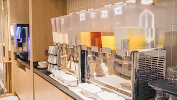 A beverage dispenser with multiple options, a coffee machine, and a counter with disposable cups.
