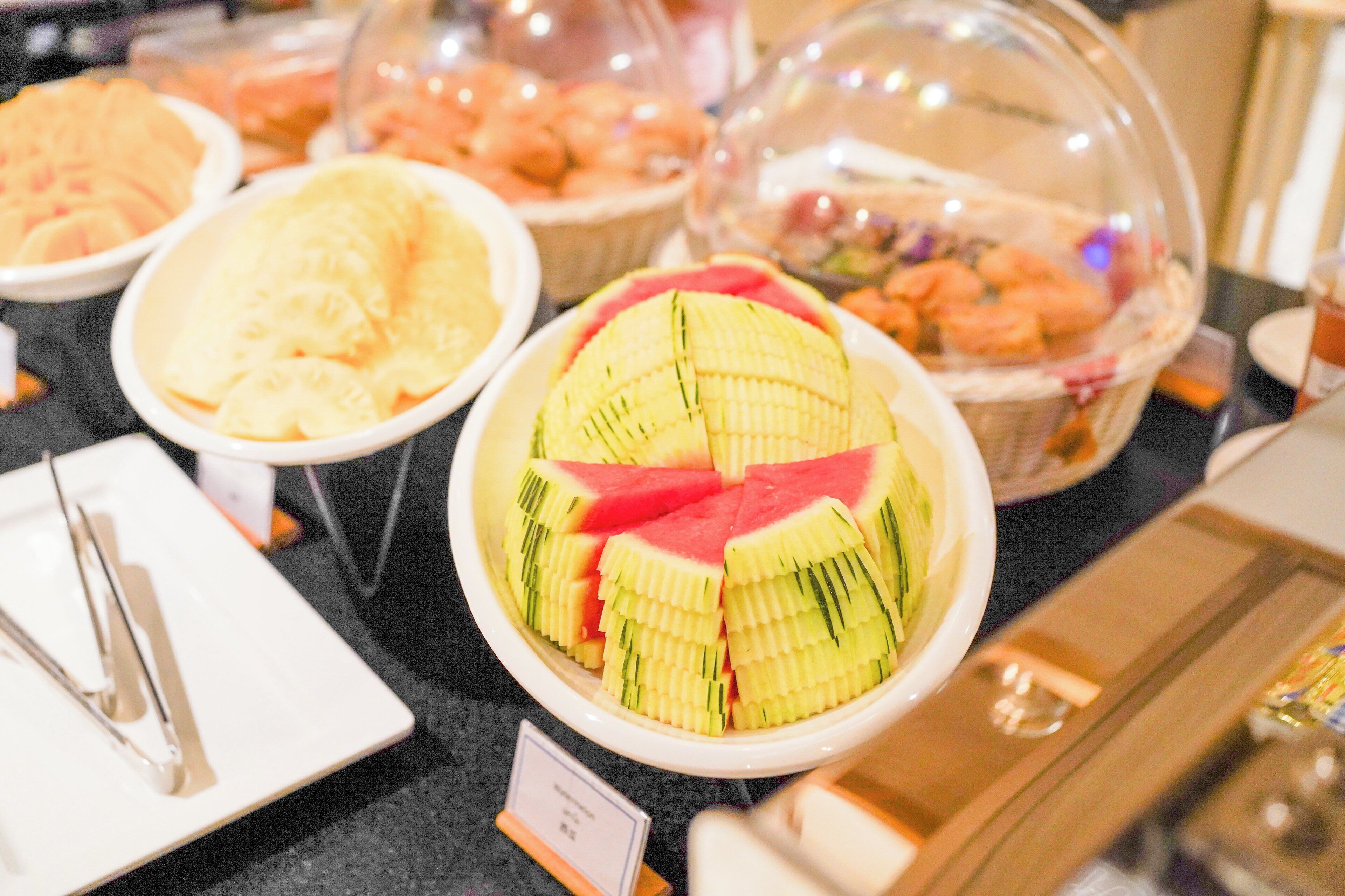 Een buffet met diverse soorten eten, waaronder gesneden fruit en gebak.