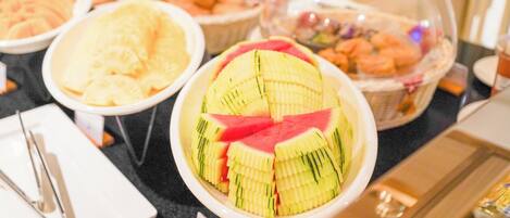 Ein Buffet mit verschiedenen Speisen, darunter Obstscheiben und Gebäck.