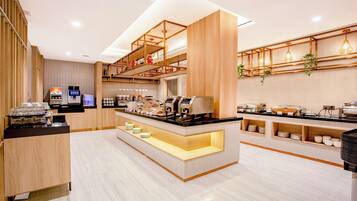 A modern cafe with a self-service coffee station, a counter with a display of pastries, and a seating area with wooden accents.