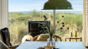 Una mesa de comedor con vista a la playa y las dunas.
