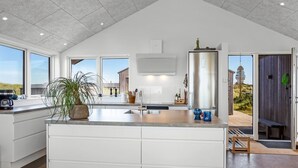 Una cocina amplia con una isla grande, un refrigerador moderno de acero inoxidable y vistas al exterior.