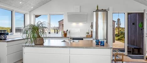 Een koelkast, een vaatwasser, kookgerei, borden en bestek