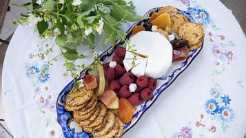 Ett bricka med ett urval av snacks, inklusive ost, torkad frukt och kex, placerat på ett broderat bordsduk.