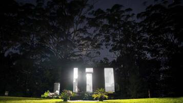 Un bâtiment doté de grandes fenêtres, entouré d’arbres et d’une zone herbeuse.