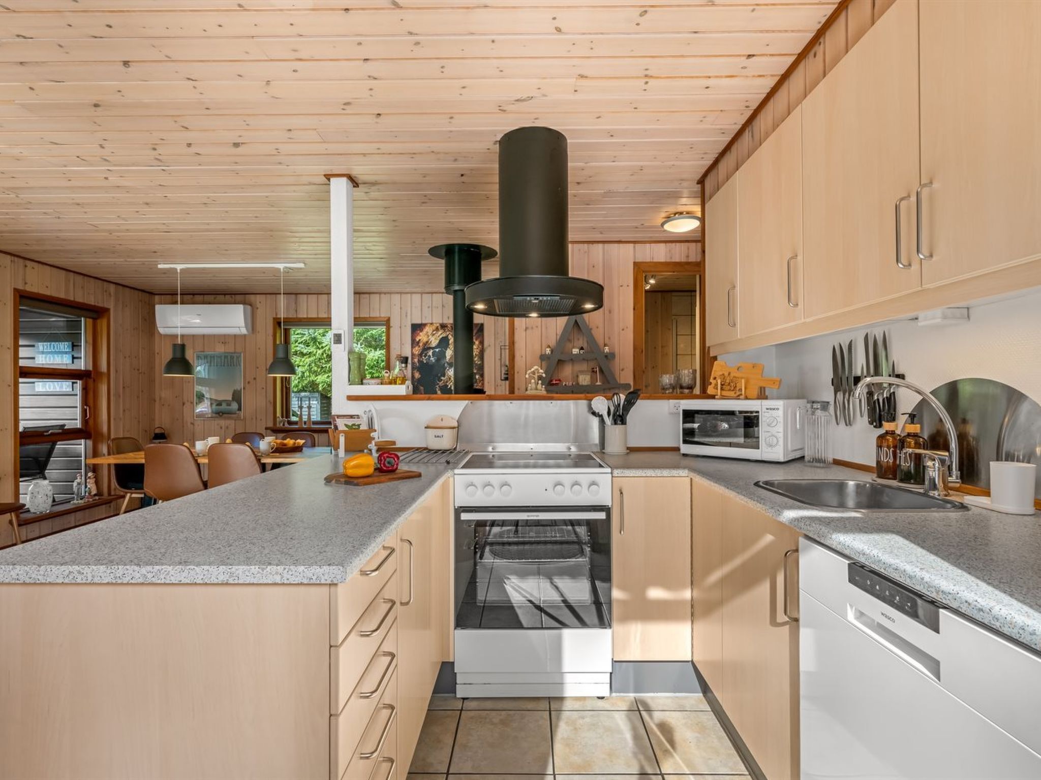 Een moderne keuken met een centraal kookeiland, een inbouwoven en roestvrijstalen apparatuur.