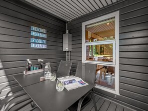 Un comedor con una mesa dispuesta para dos, una ventana con vistas al exterior, y un letrero en la pared que dice 'WELCOME HOME FAMILY LOVE'.
