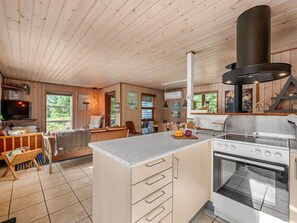 Une cuisine moderne dotée d’un îlot central, d’une cuisinière et d’une grande hotte noire.