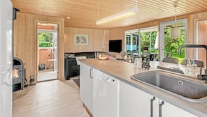 A modern kitchen with wooden paneling, a central island with a sink, and a built-in dishwasher. - "Bistra" - 400m from the sea by Interhome (Løkken)