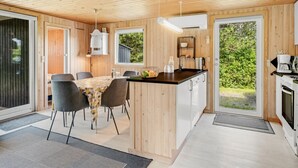 A modern kitchen with a central island, dining area with chairs, wooden walls, and large windows. - "Bistra" - 400m from the sea by Interhome (Løkken)