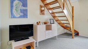 A room with a TV, a white cabinet, a wooden staircase, and a framed map on the wall. - "Aya" - 2.3km from the sea by Interhome (Rømø)