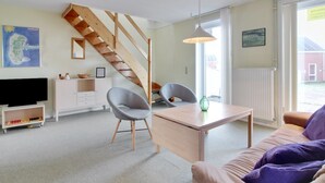 A modern living room with a wooden staircase, a flat-screen TV, a dining table, and a sofa with a purple throw. - "Aya" - 2.3km from the sea by Interhome (Rømø)