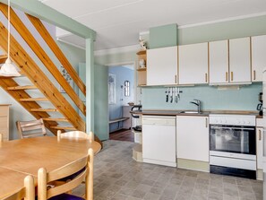 A kitchen with white cabinets, a wooden staircase, and a dining table with chairs. - "Lynne" - 2.3km from the sea by Interhome (Rømø)