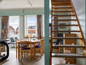A dining area with a table and chairs, a staircase with a cat tree, and a view of the outside. - "Lynne" - 2.3km from the sea by Interhome (Rømø)