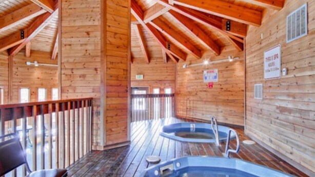 Una baita di legno con una vasca idromassaggio e una sedia.