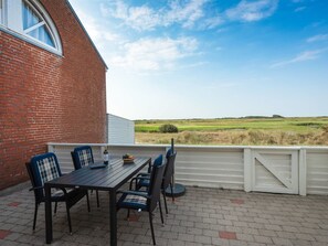 Eine Terrasse im Freien mit Tisch und Stühlen, einer Weinflasche und Blick auf einen Golfplatz.
