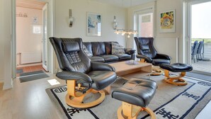 Un salon moderne avec un canapé en cuir, deux fauteuils en cuir, une table basse et un tapis à motifs.