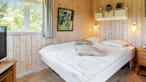 Ein Zimmer mit Holzwänden, einem Bett, einem Fernseher und einem Regal mit Dekoration.