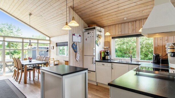Eine moderne Küche mit Holzausstattung, einer zentralen Kochinsel und einem Essbereich mit Stühlen.