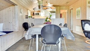 A dining area with a striped tablecloth, black chairs, and a central flower arrangement.
