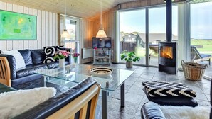 A modern living room with a glass coffee table, leather sofa, and a fireplace.