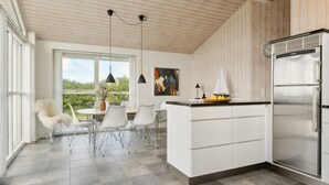 A modern kitchen with a central island, white cabinetry, and a stainless steel refrigerator. - "Ohto" - 281m from the sea by Interhome (Hjørring)