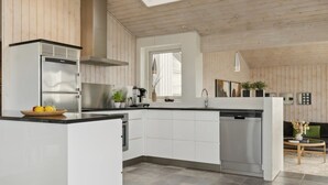 A modern kitchen with white cabinetry, a built-in dishwasher, and a large island with a black countertop. There are skylights on the ceiling, providing natural light. - "Ohto" - 281m from the sea by Interhome (Hjørring)