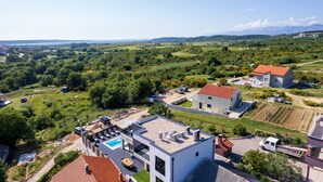 A modern house with a rooftop pool, surrounded by lush greenery and a clear view of distant mountains. - Kala in Razanac With 4 Bedrooms and 2 Bathrooms (Razanac)